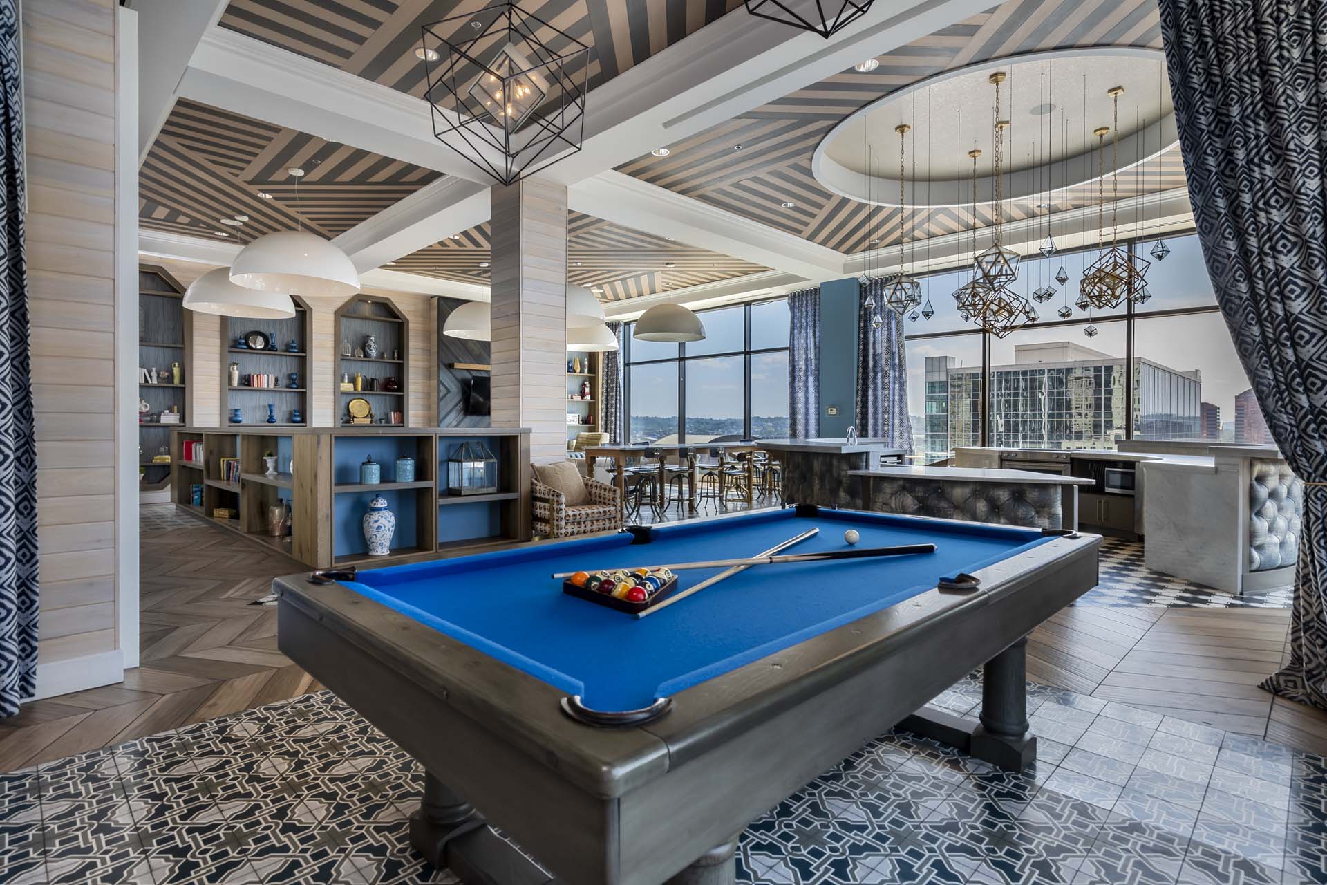 Luxury game room with a pool table, bar seating, and large city-view windows