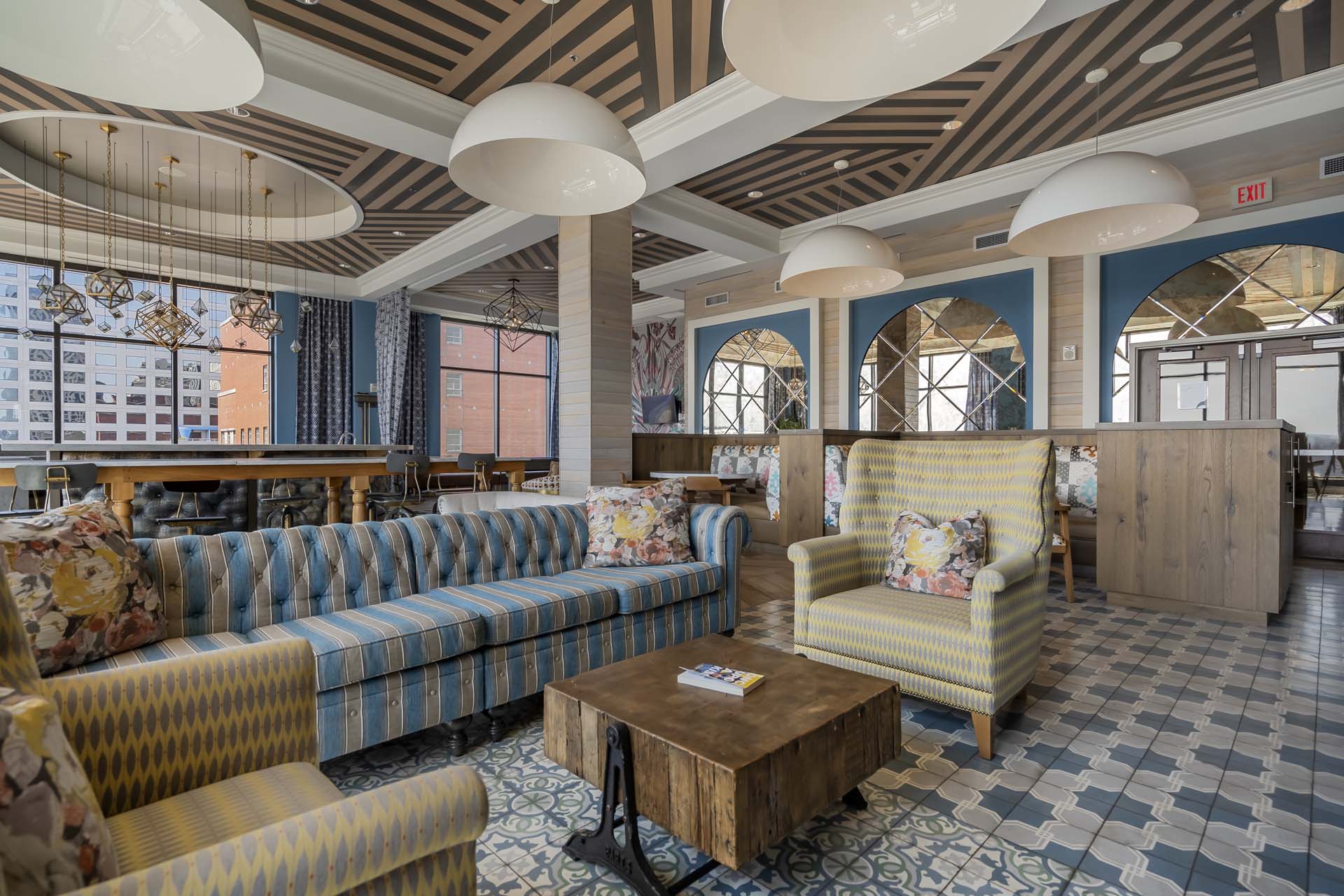 Stylish hotel lounge with patterned seating, hanging lights, and large windows